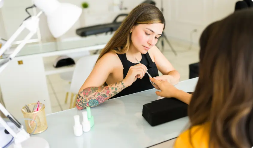 Nail technician painting a client's nails in a salon